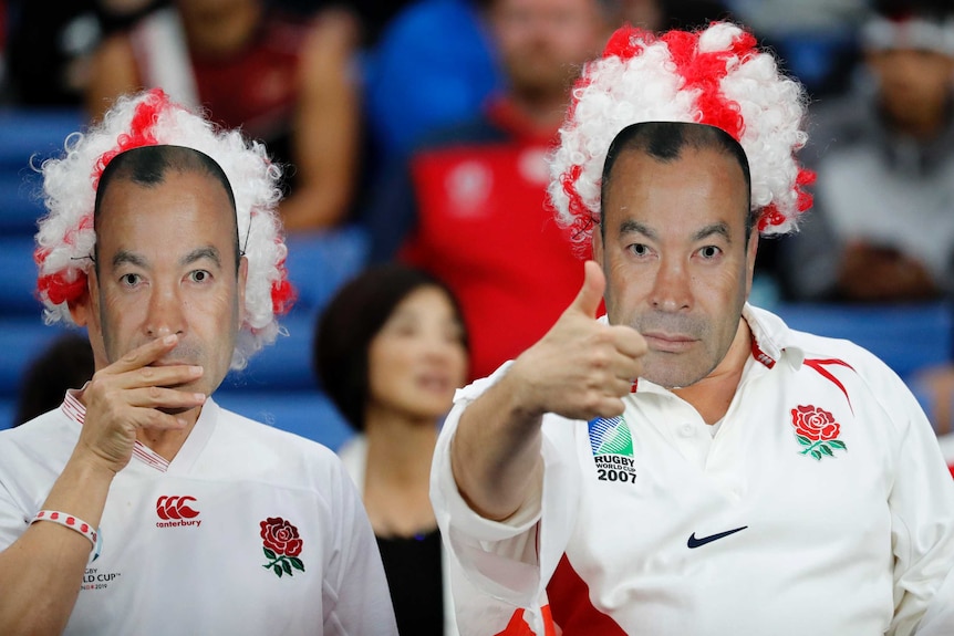 England supporters wearing Eddie Jones masks give the thumbs up at the World Cup semi-final against New Zealand in Yokohama.