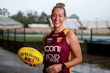 Brisbane Lions player Lauren Arnell smiles as she holds a football at training in Brisbane.