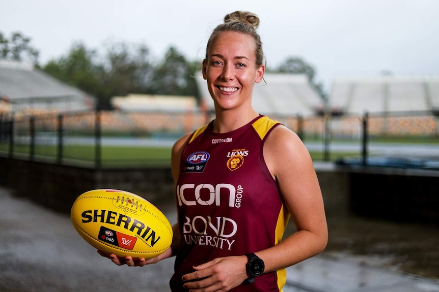 Brisbane Lions player Lauren Arnell smiles as she holds a football at training in Brisbane.