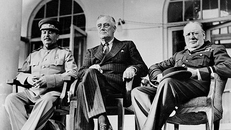 A black-and-white historical image of Josef Stalin, Franklin D Roosevelt and Winston Churchill sitting at a conference.