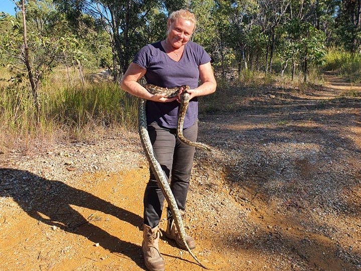 Woman holding python in bushland
