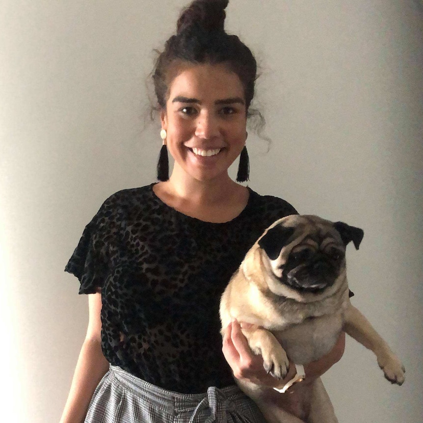 Tahlea Aualiitia holding a pug dog and wearing clothes she already owns rather than buy new ones