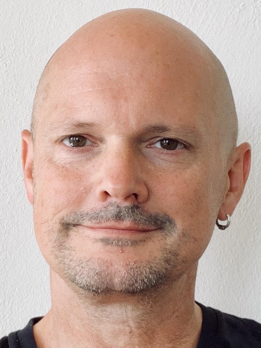 Close up portrait of a smiling bald man with a silver earring 