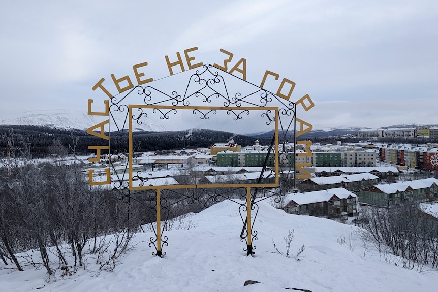 A view of the town of Kharp seen through a frame with the words "Happiness is not over the hill" in Russian.