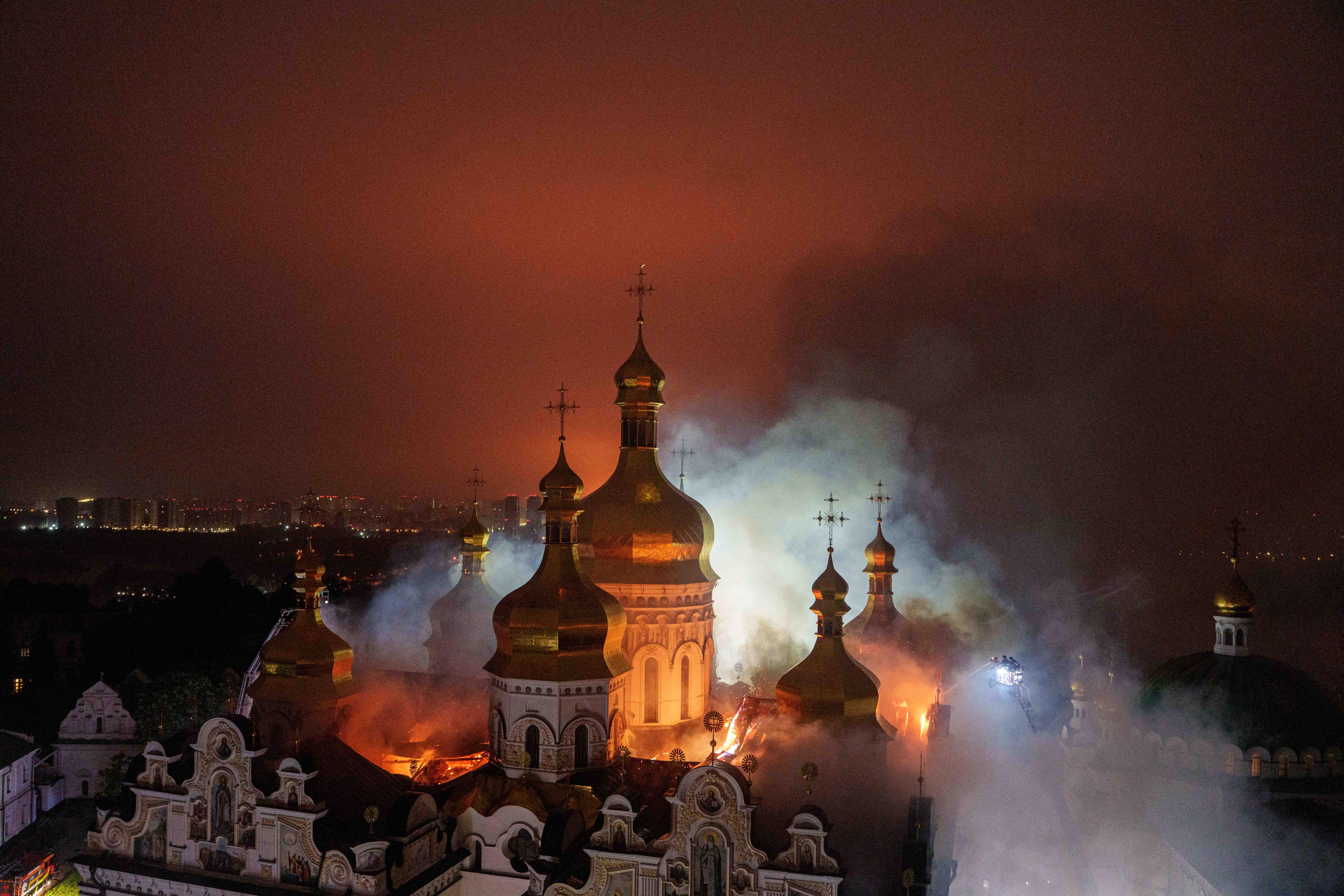 Golden domes of a cathedral on fire at night.
