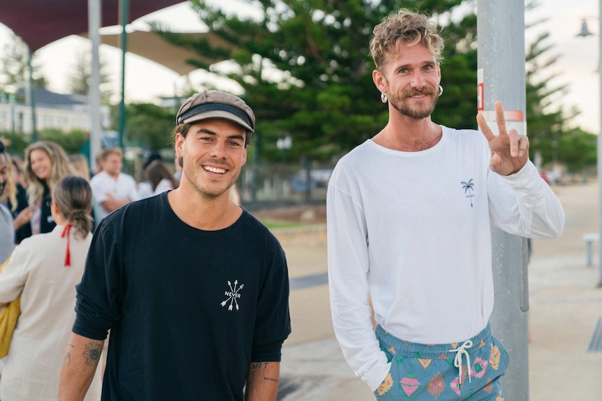 Two young men pose for a photo at a cafe