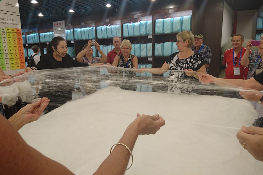 Australian women holding silk threads at a Chinese silk factory