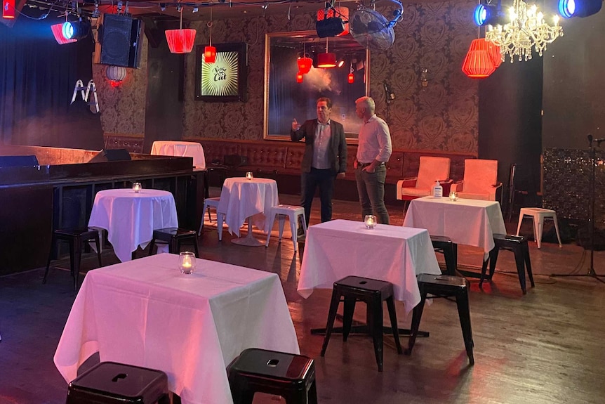 Tables covered in white cloths on a nightclub dance floor.