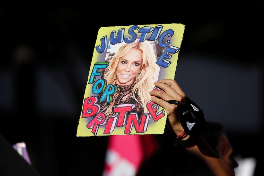 A supporter of singer Britney Spears holds up a picture of the pop star with the words "Justice for Britney