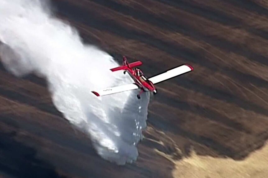A water bomber drops its load on a fire ground at Templers.
