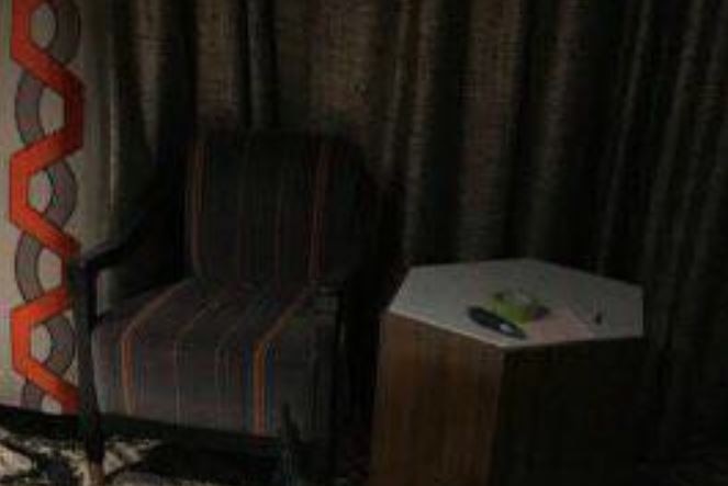 A chair is seen in Stephen Paddock's hotel room next to a small table with a piece of paper and a pen.