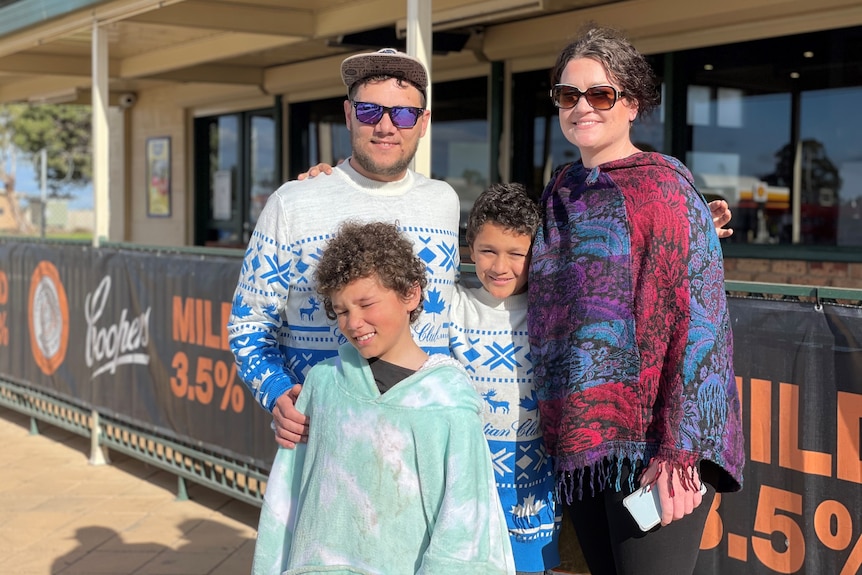 A man wearing a blue and white jumper and a baseball cap with a woman wearing a pashmina and two children