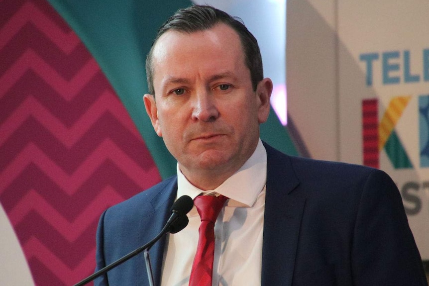 Mark McGowan standing on a podium and speaking into a microphone at a lectern.