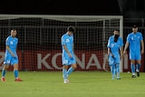 Soccer players wearing light blue look dejected after losing a game
