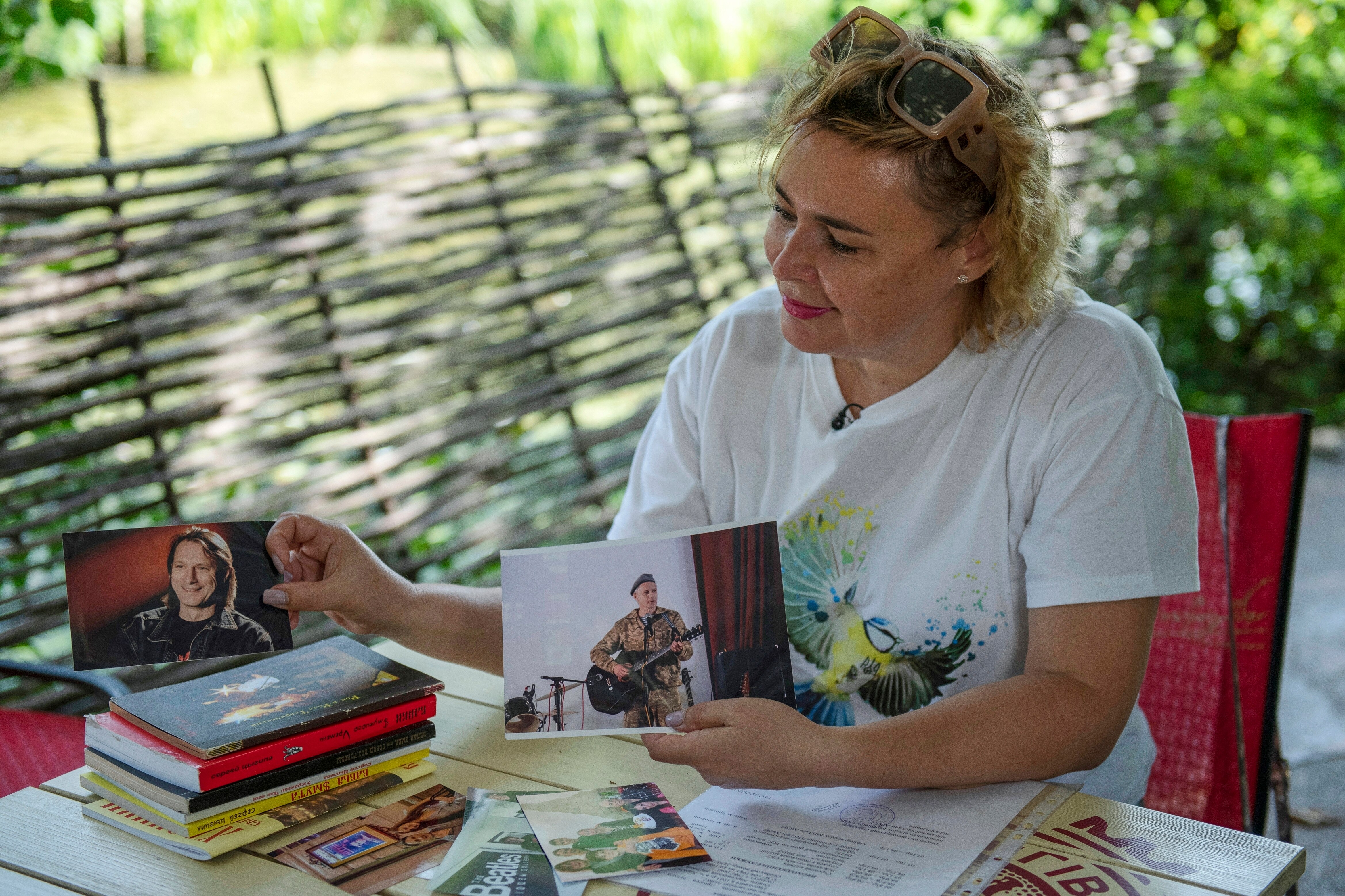Seated woman holds up two pictures of her husband.