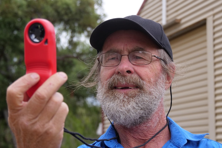 Close up of man with beard looking at red weather reading device
