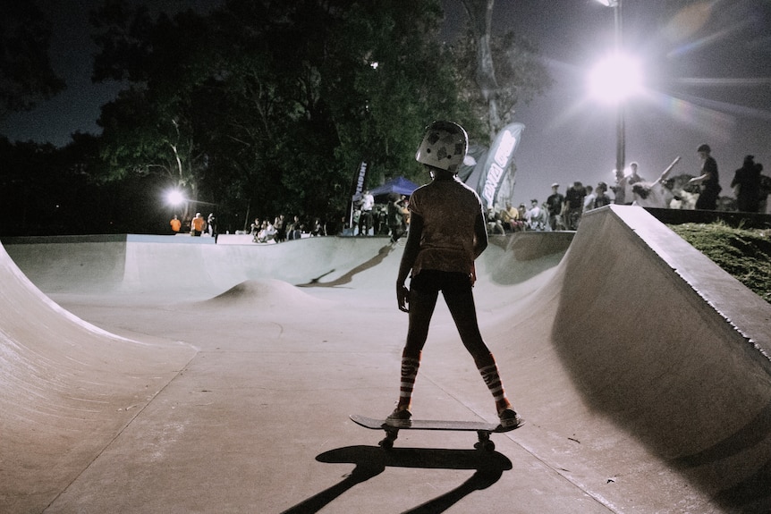 young girl on skateboard in front of big light