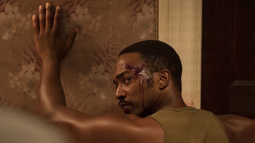 Still image from 2017 film Detroit of actor Anthony Mackie with his hands against the wall and head bloodied.