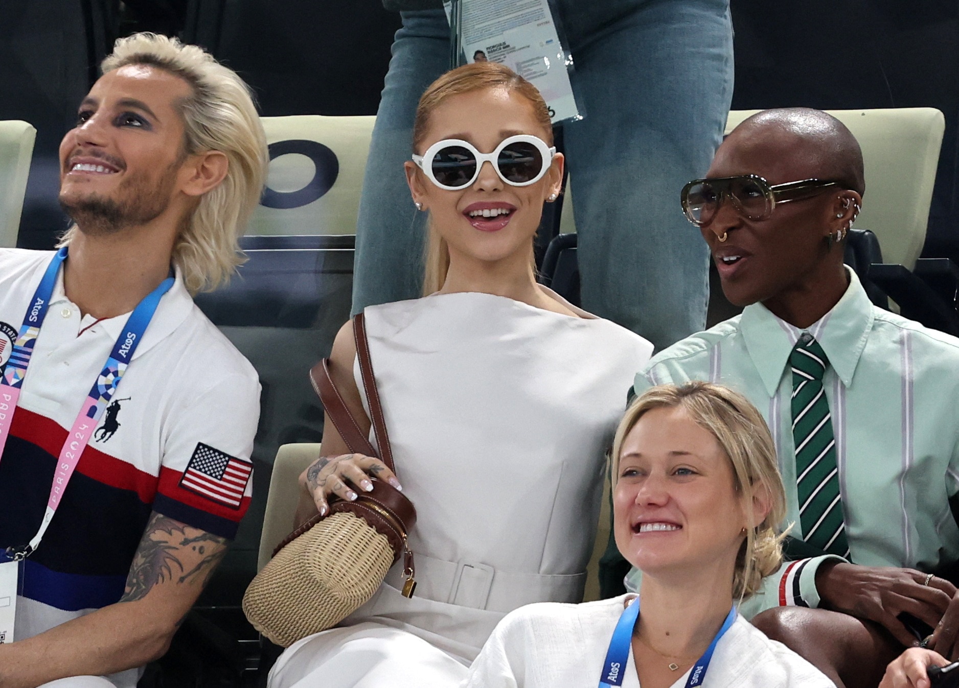 Ariana Grande centre in white dress and round sunglasses and cynthia erivo in a green shirt and tie 