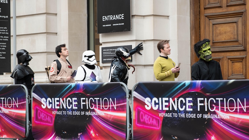 Members of the public line up with aliens to view the Science Friction exhibition at the London Science Museum.