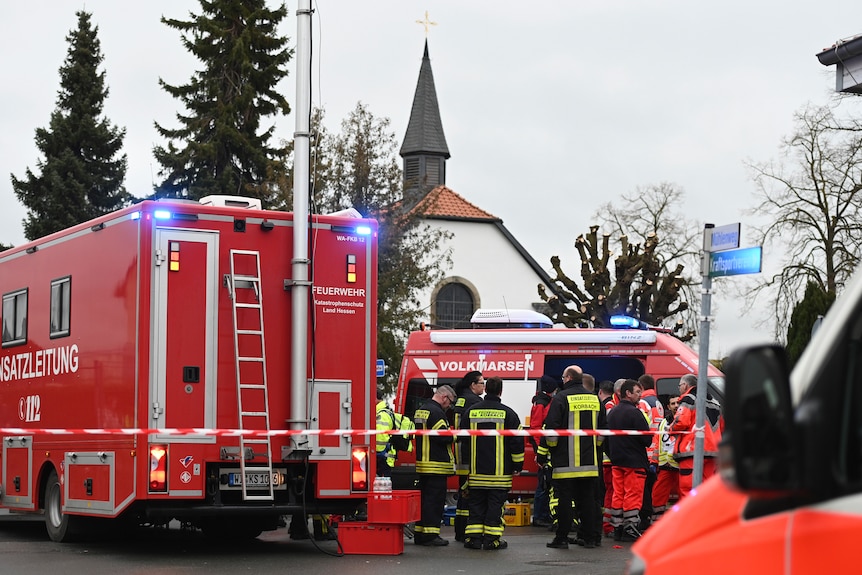 Rescue workers stand next to two emergency vehicles.