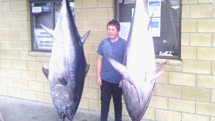 Sam Nichols stands between two tuna
