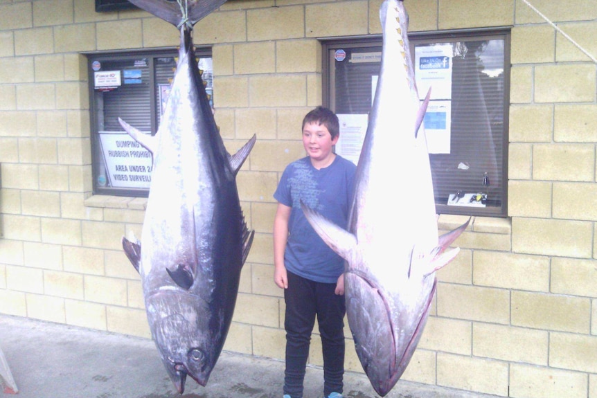 Sam Nichols stands between two tuna