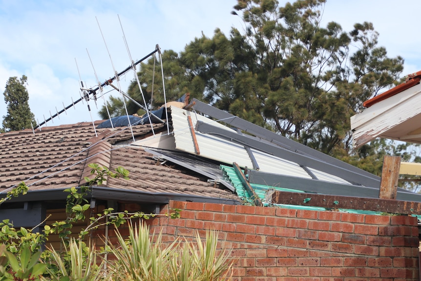 An aerial appears knocked over by a patio that has flipped onto a roof