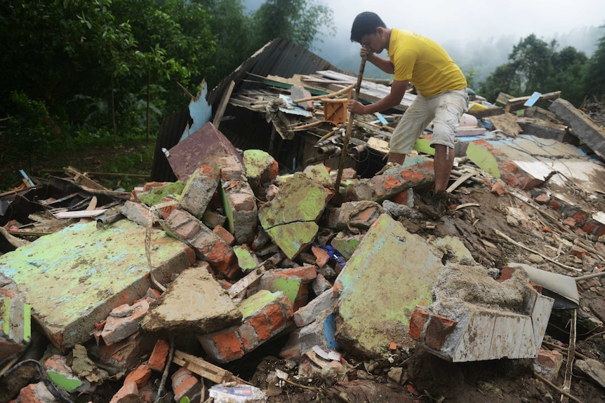 An Indian man searches for bodies of those killed in a landslide