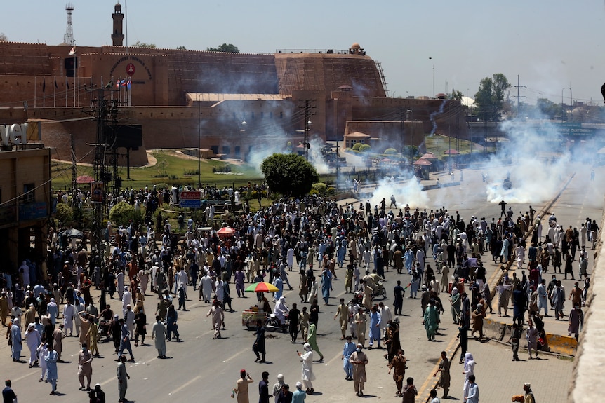 Picture of a large crowd on a road in front of an old building 