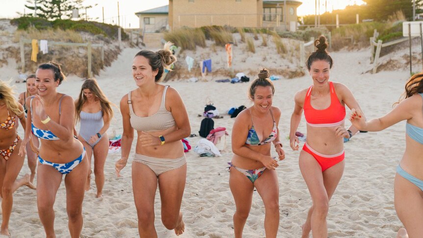A group of girls running along the shore at a beach