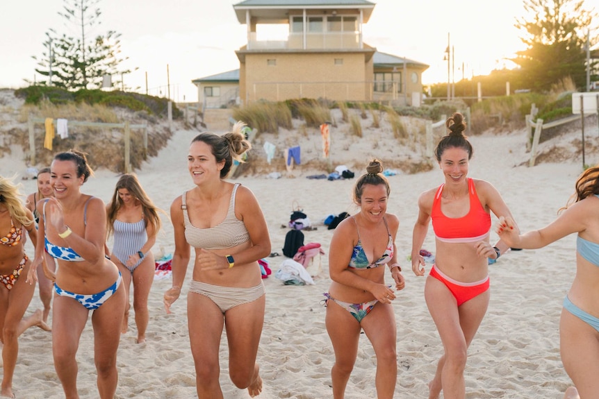 A group of girls running along the shore at a beach