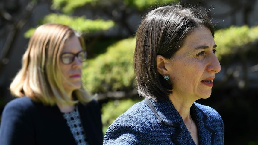 Two woman, looking to the side, with concerned expressions on their faces