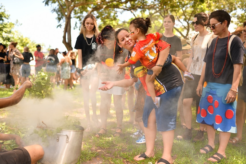 A woman holds a child at a ceremony in Darwin.