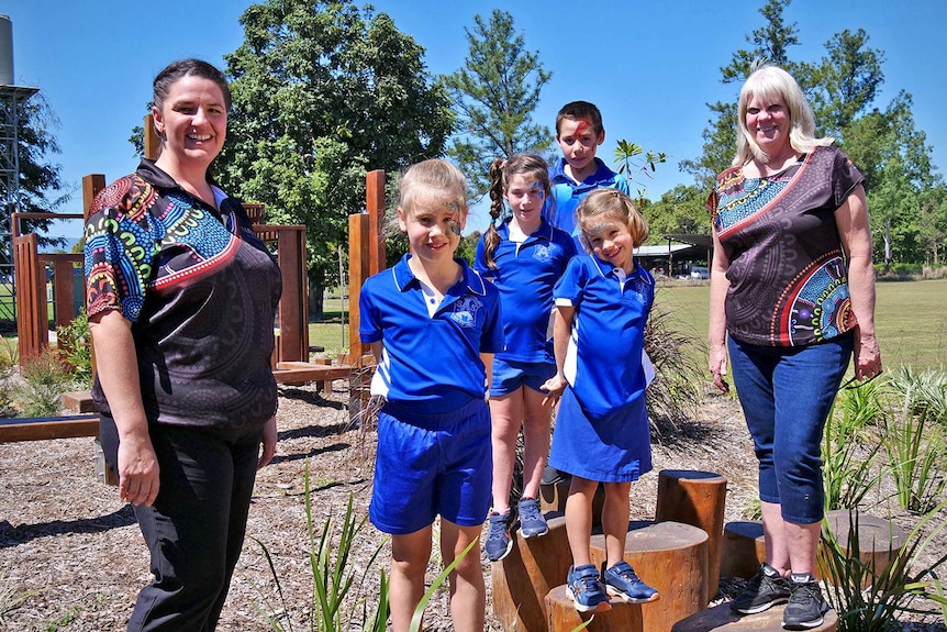 The four students from Abergowrie State School stand in their adventure playground flanked by the principal and teacher