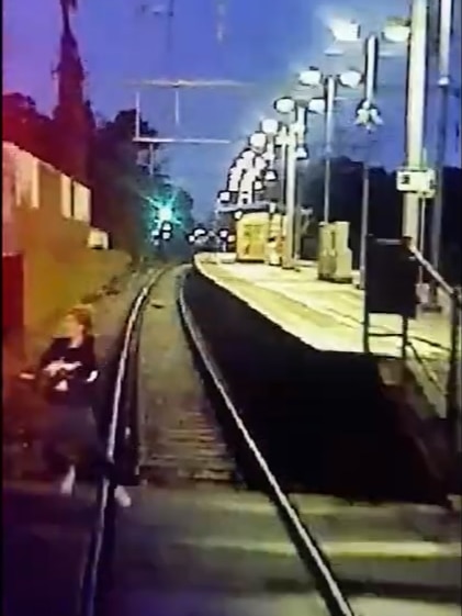 A woman stepping onto tracks from the view of a train