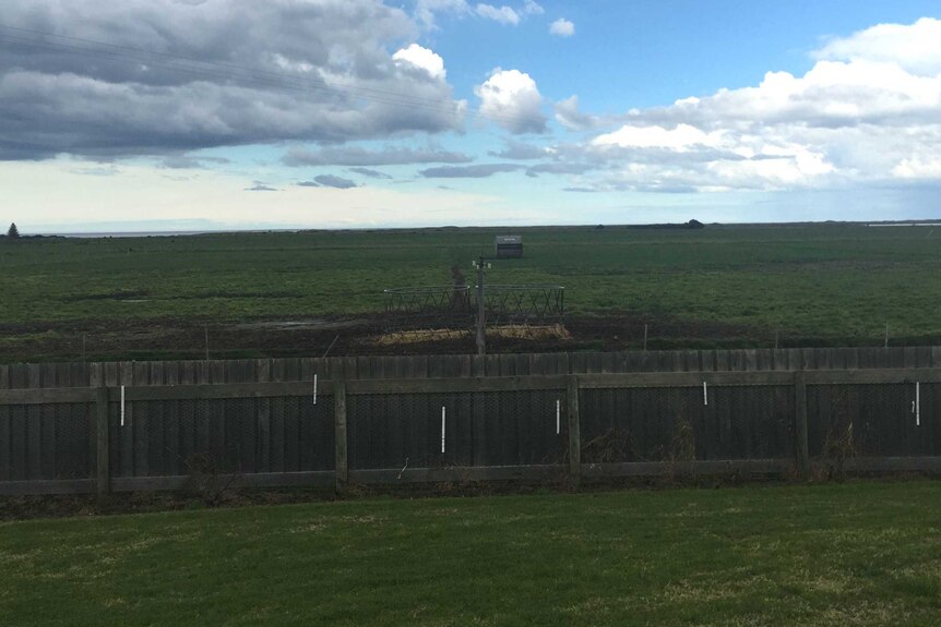 A green field on Julie Boulton's dairy farm in Gippsland, in Victoria's south-east. Over the fence is a gas well.