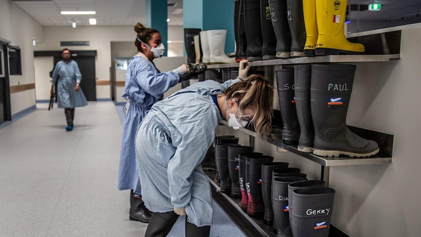 Morgue workers putting on gumboots in preparation for a procedure