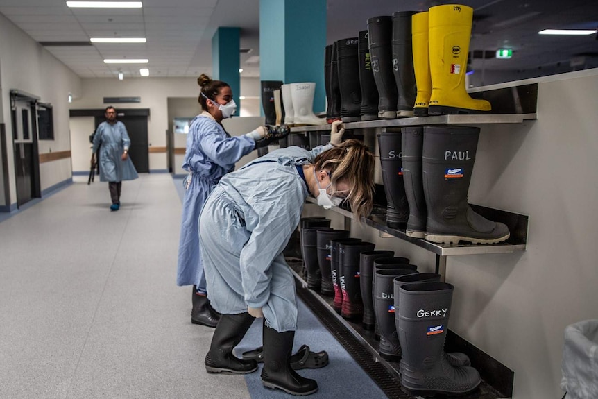 Morgue workers putting on gumboots in preparation for a procedure