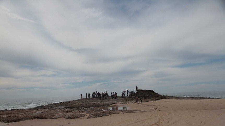 People standing on a rock by the sea