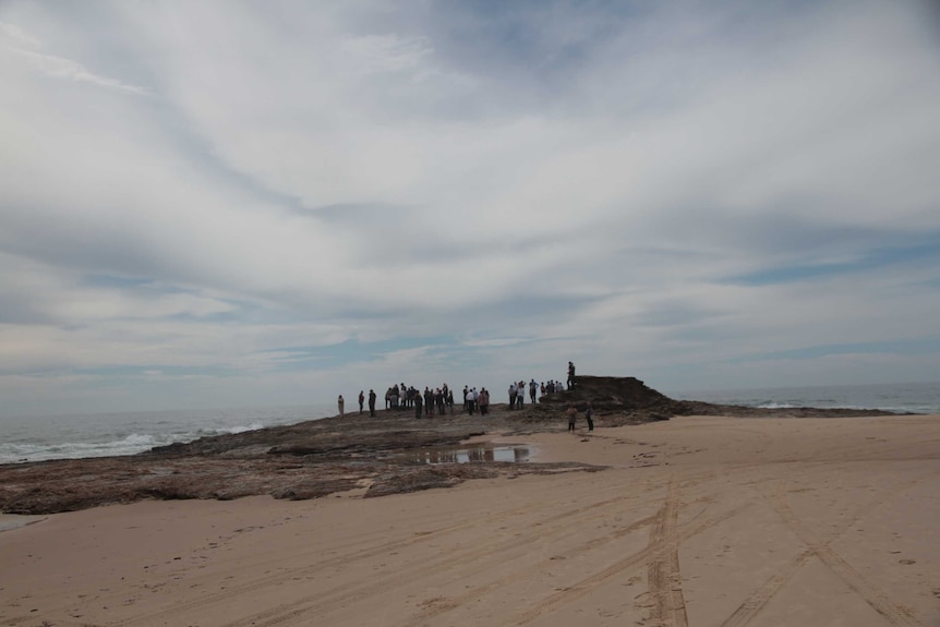 People standing on a rock by the sea