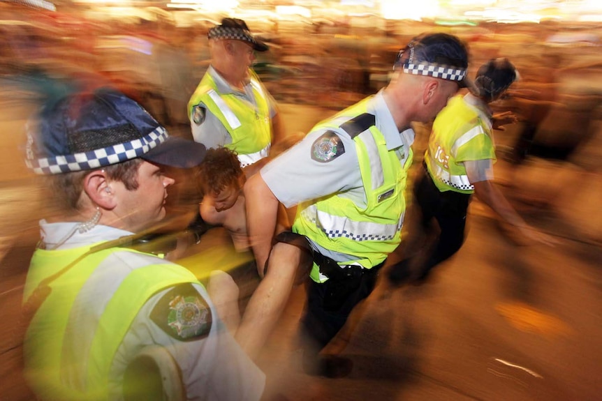 A blurry image of police apprehending a young person on the Gold Coast.