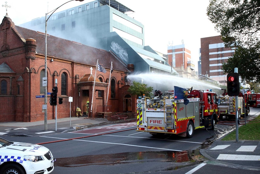 A jet of water is sprayed onto the Greek Orthodox Church from one of the fire engines.