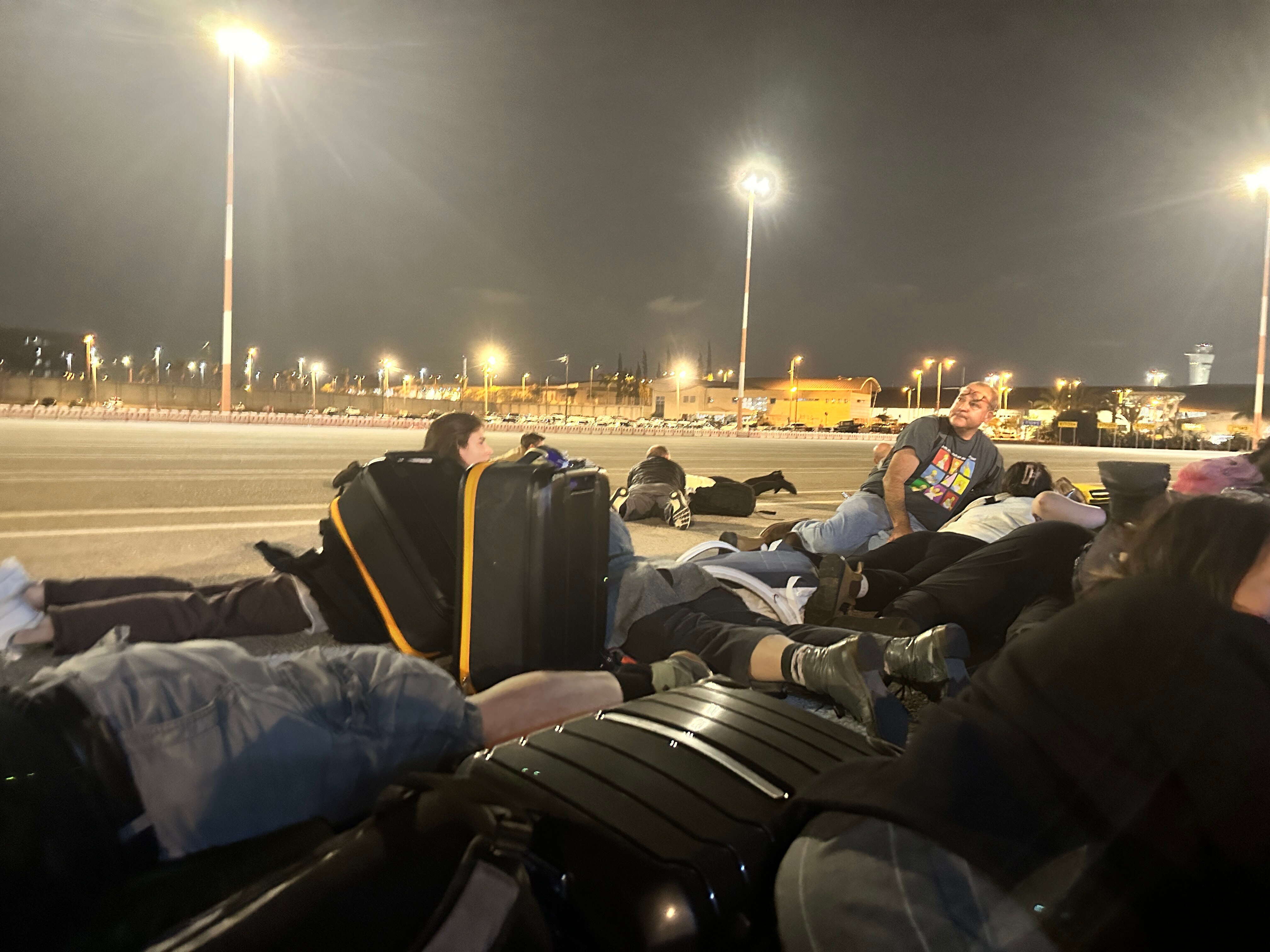 Group of people lying on tarmac at night.