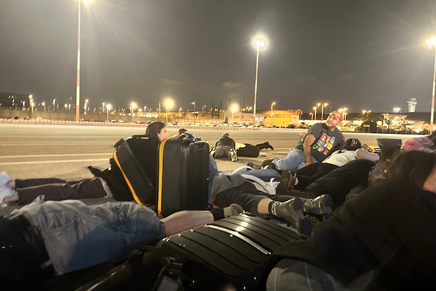 Group of people lying on tarmac at night.