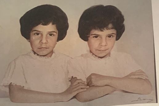 Two little girls with arms linked looking at the camera