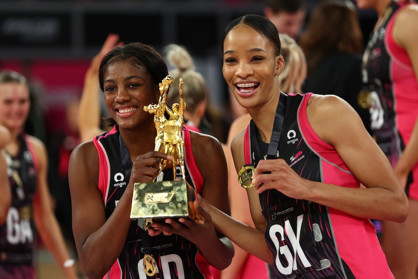 Two Jamaican players hold the Super Netball trophy