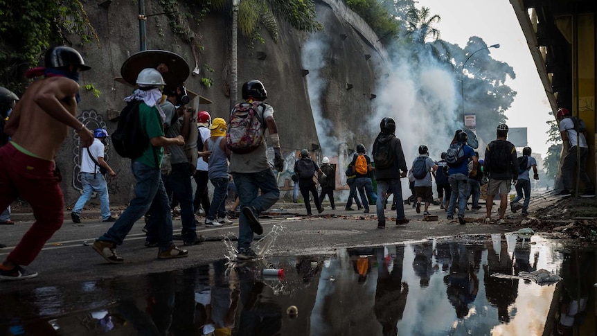 Men run past a large puddle towards a protest