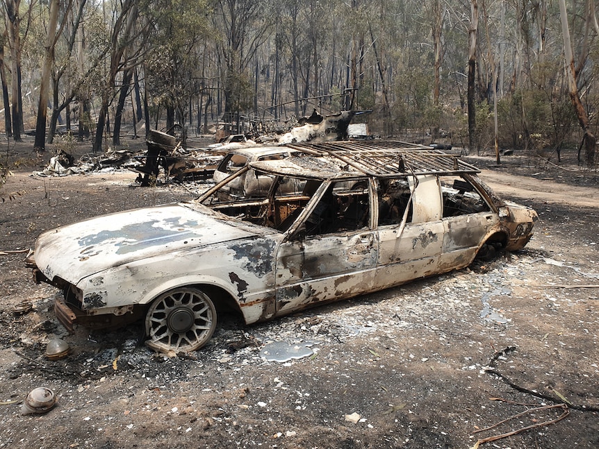 Bushfire damaged car in bushland.