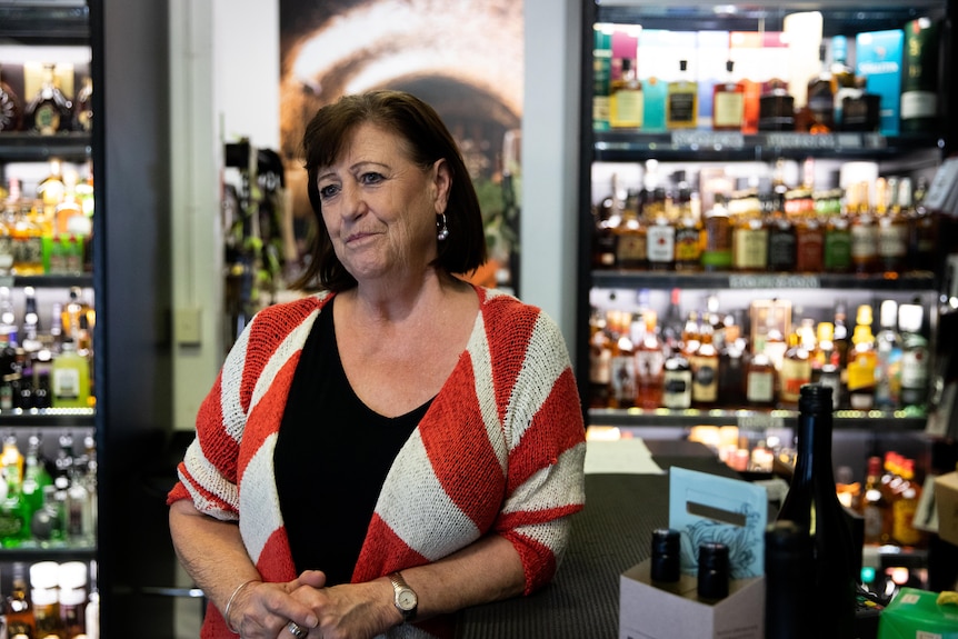 A woman standing in a liquor store filled with bottles on shelves.
